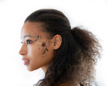 Frau mit schwarzen temporären Tattoo auf der Wange